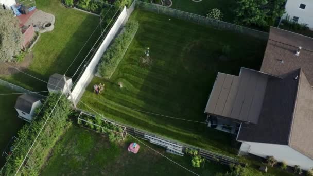 Images aériennes du haut du tracteur de pelouse fauchant la pelouse par le haut sur la cour arrière — Video