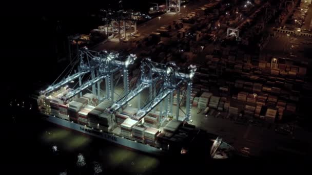 Luftaufnahmen. Frachtschiff mit Frachtcontainern steht nachts auf einem Liegeplatz im Hafen beim Be- und Entladen von Containern.. — Stockvideo