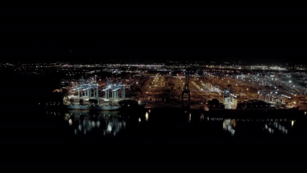 Breed zicht op vrachtschip met vrachtcontainers op een ligplaats in de haven bij het laden en lossen van containers 's nachts — Stockvideo