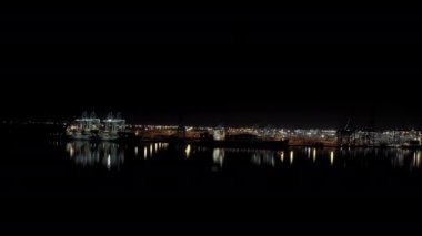 Kargo gemisinin kargo konteynırlı geniş görüntüleri gece vakti konteynırların yüklenip boşaltıldığı limandaki bir rıhtımda duruyor.