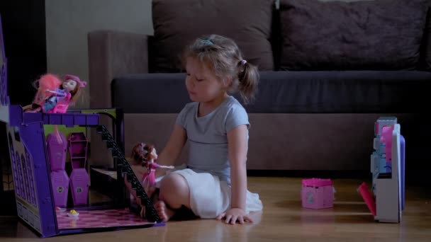 Uma menina de seis anos a brincar no quarto com bonecas. Amplo tiro em câmera lenta — Vídeo de Stock