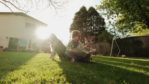 Küçük çocuk bahçede köpekle oynuyor. — Stok video
