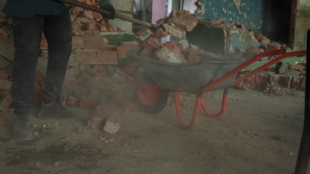 Робітник використовує інвалідний візок для видалення будівельних сміття. Знесення і перестановка. Повільний рух — стокове відео
