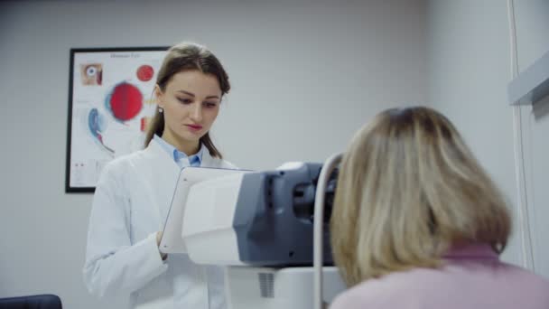 De oogarts onderzoekt het oog van de patiënt en kijkt vervolgens in de camera. Breed beeld — Stockvideo