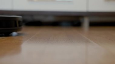 Akıllı Elektrikli süpürge robotunun oturma odasındaki ahşap zeminde koşuşunun yakın görüntüsü