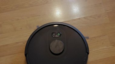 Akıllı Elektrikli süpürge robotu oturma odasında ahşap zeminde çalışıyor.