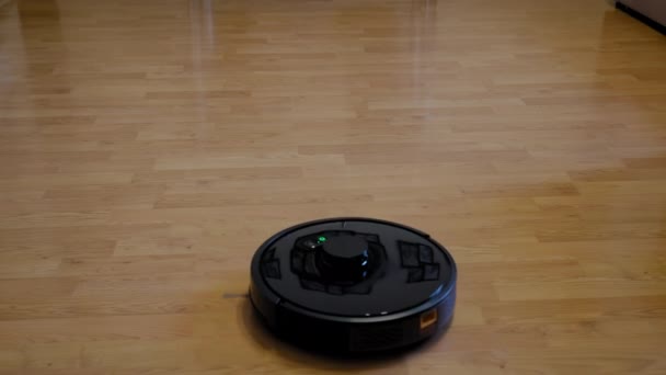 Vista superior. Robot aspirador inteligente funciona en el suelo de madera en una sala de estar — Vídeo de stock