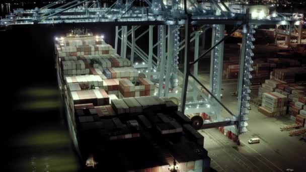 Ευρεία θέα μη επανδρωμένου. Φορτηγό πλοίο με εμπορευματοκιβώτια στέκεται σε μια κουκέτα στο λιμάνι κατά τη φόρτωση και εκφόρτωση των εμπορευματοκιβωτίων τη νύχτα.. Νέα Υόρκη sep 2021, ΗΠΑ — Αρχείο Βίντεο