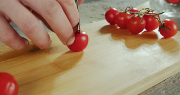 Close up fooage van chef-koks handen snijden van een verse tomaat met mes op houten plank. — Stockvideo