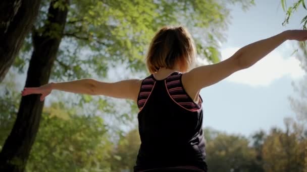 ヨガマットに座って、晴れた日に屋外でヨガストレッチ運動を練習する女性。閉じろ! — ストック動画