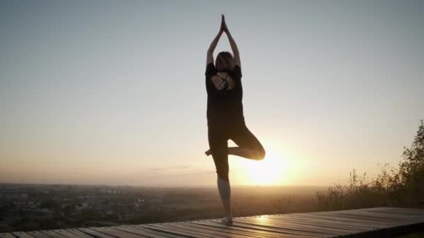 Stand femme sur tapis de yoga et pratique d'exercices d'étirement de yoga à l'extérieur au coucher du soleil — Video