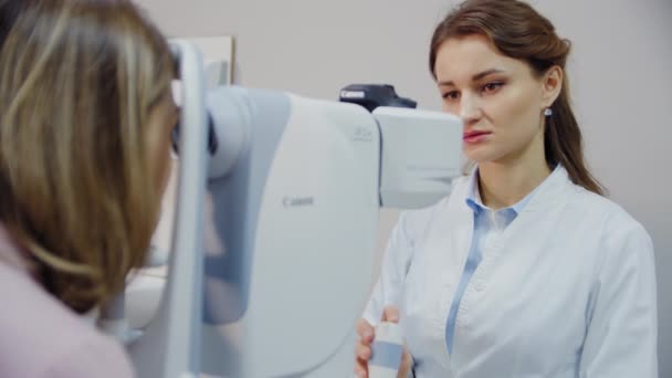 El oftalmólogo examina el ojo de los pacientes y luego mira a la cámara. Vista de cerca — Vídeo de stock