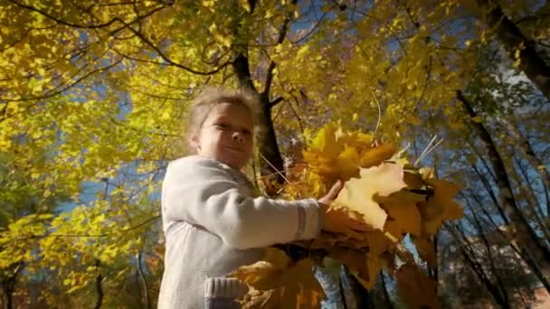 Kleines Mädchen wirft gelbe Herbstblätter, Zeitlupe — Stockvideo