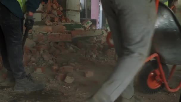 O trabalhador usa um carrinho de mão para remover detritos de construção. Trabalho de demolição e rearranjo. Filmagem em câmara lenta — Vídeo de Stock