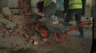 İşçi inşaat enkazını kaldırmak için bir el arabası kullanıyor. Yıkım işleri ve yeniden düzenleme. Yavaş çekim.