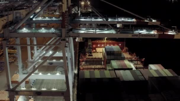 Un drone aérien. du navire de charge avec des conteneurs de fret se trouve sur un poste d'amarrage dans le port au chargement et au déchargement des conteneurs la nuit. New York sep 2021, États-Unis — Video