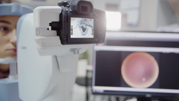 Okulista bada oko pacjenta, a potem patrzy w kamerę. Zbliżenie widoku — Wideo stockowe