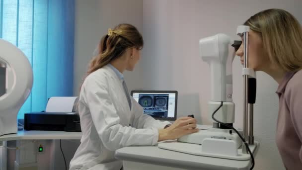 Oftalmologen undersöker patientens öga och tittar sedan in i kameran. Bredbildsfilm — Stockvideo
