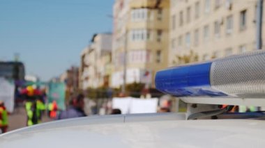 Polis arabası lambası yanıp sönen sinyal şehrin caddesinde duruyor. Görüntüleri kapat