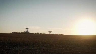 Gün batımında iki telekomünikasyon anteninin ya da radyo teleskop çanağının geniş hava insansız hava aracı görüntüsü