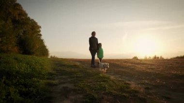 Küçük kızı olan bir kadın parkta köpeği gezdiriyor. seyahat konsepti. Geniş Yavaş çekim görüntüleri
