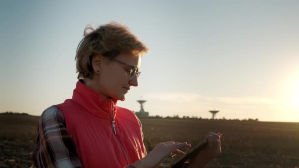 Žena obsluha zařízení tablet počítač ovládá solární radioteleskop antény. Záběry širokého pohledu — Stock video