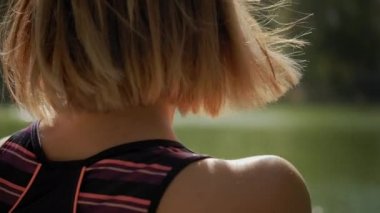 Yoga minderinde oturan ve güneşli bir günde dışarıda yoga esneme egzersizi yapan bir kadın. Yakın çekim.