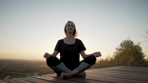 Žena na józe podložka a cvičení jóga strečink cvičení venku při západu slunce — Stock video
