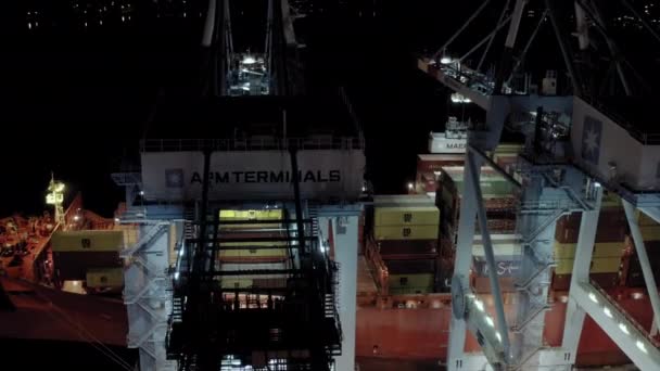 Um drone aéreo disparado. Navio de carga com contêineres de carga fica em um cais no porto no carregamento e descarga de contêineres à noite. Nova Iorque sep 2021, EUA — Vídeo de Stock