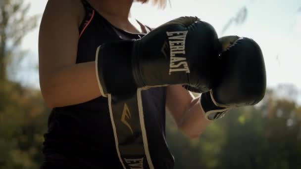 Женщина носит боксерские перчатки, стоит против солнца. Львов 20 сентября 2021 года — стоковое видео