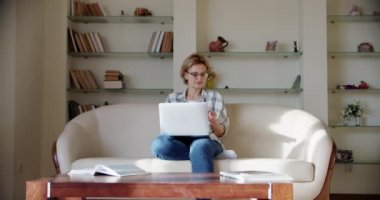 Kadın dizüstü bilgisayara bak, kanepeye otur, telefonda konuş.