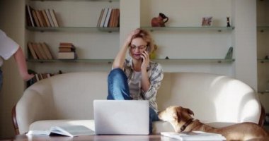 Yorgun bir eş, gürültülü küçük bir kız çığlık atarken, kanepede zıplarken ve koca odada temizlik yaparken rahatsız bir şekilde kanepede oturuyor. Yavaş çekim