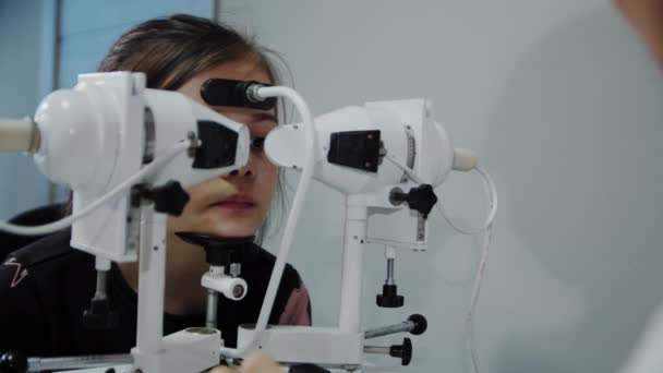 Okulista bada oko młodych pacjentów, a następnie patrzy w kamerę. Zamknij się. — Wideo stockowe