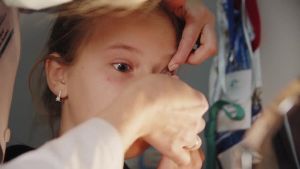 Młoda dziewczyna w recepcji okulisty, z soczewką w oku — Wideo stockowe