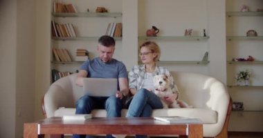 Yorgun karı koca koltukta otururken gürültücü küçük kız anne babalarının yanında kanepede zıplayarak bağırıyor. Yavaş çekim