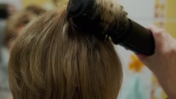 Donna che si asciuga i capelli con un asciugacapelli in bagno davanti a uno specchio — Video Stock