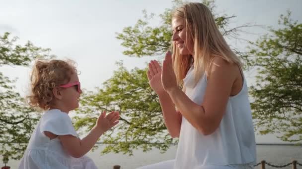 แม่และลูกสาวเล่นเกมปรบมือในสวนตอนพระอาทิตย์ตก การเคลื่อนไหวช้า — วีดีโอสต็อก