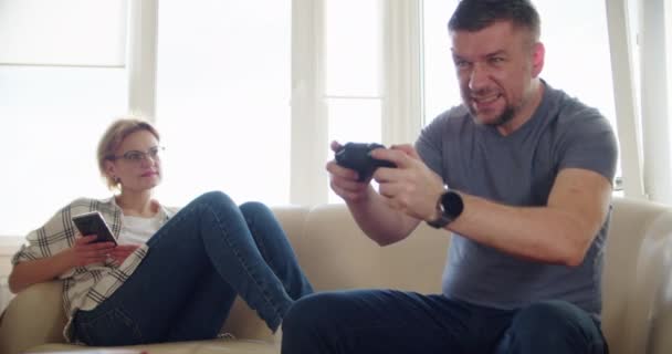 Mişcare lentă. Un cuplu fericit stând pe canapea și jucând jocuri video, folosind controlere în dragoste s-au distrat jucând împreună în jocuri video online. — Videoclip de stoc