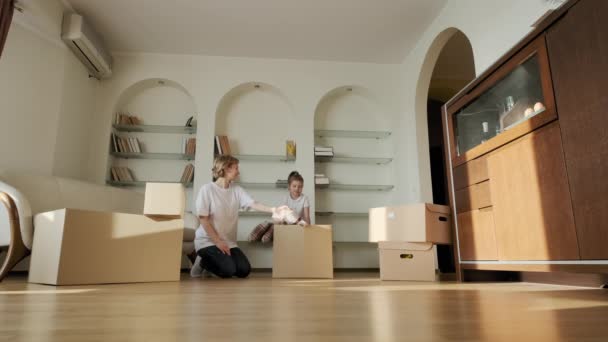 Heureux jeunes parents courir pousser boîtes en carton avec petite fille mignonne filles monter à l'intérieur et les animaux de compagnie chien Jack Russel, les propriétaires de la famille jouer à s'amuser le jour du déménagement — Video