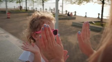 Anne ve kızının gün batımında parkta el çırpma oyunu oynamalarını yakından izleyin. yavaş çekim