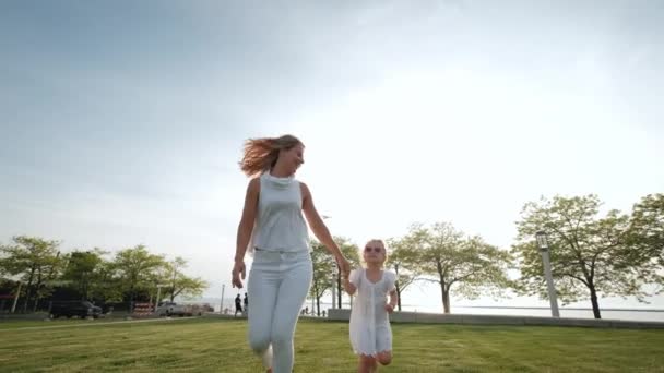 在阳光灿烂的日子里，妈妈和女儿在公园里一起跑步。大范围射击 — 图库视频影像