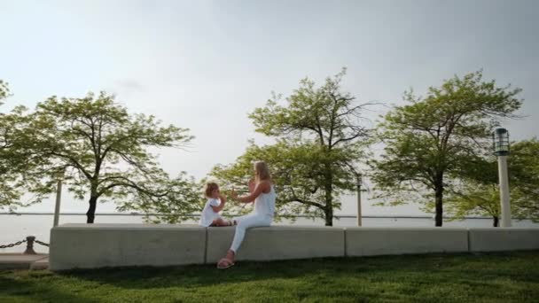 Mom and daughter playing clapping game in the park at sunset. slow motion Wide shot — Stock Video