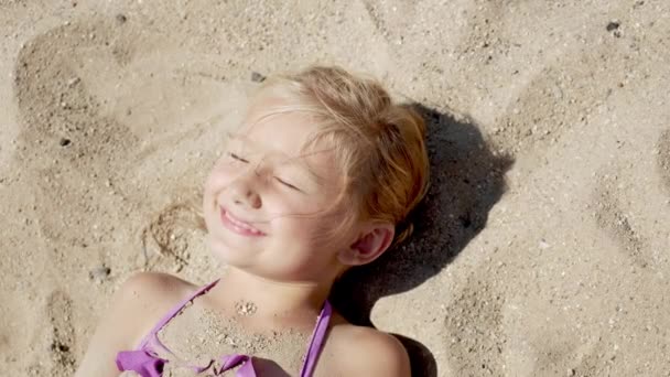 Osamělé dítě dívka ležící na pláži v písku. — Stock video