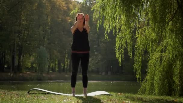 The girl performs warm-up exercises before yoga in nature n park. Slow motion, wide shot — Video Stock