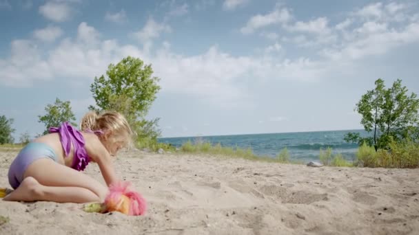 Osamělé dítě si hraje s pískem na mořské pláži v písku. Široký pohled — Stock video