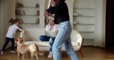 Yorgun bir eş, gürültülü küçük bir kız çığlık atarken, kanepede zıplarken ve koca odada temizlik yaparken rahatsız bir şekilde kanepede oturuyor. Yavaş çekim görüntüleri