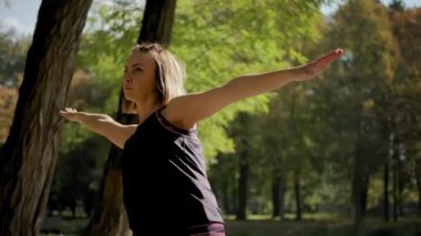 Kadın yoga minderinin üzerinde durup güneşli bir günde dışarıda egzersiz yaparken yakın plan görüntüsü. Yavaş çekim görüntüleri