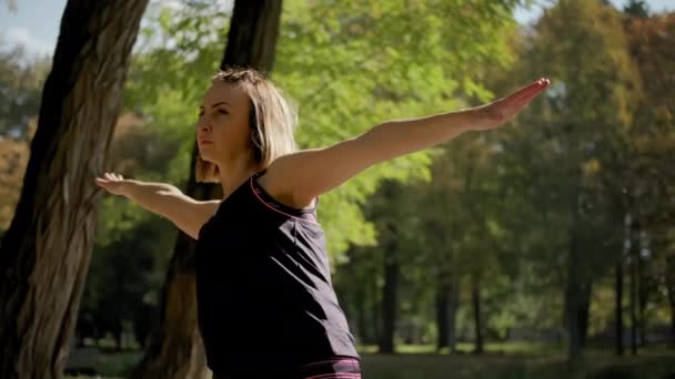 Закройте вид на женщину, стоящую на коврике для йоги и практикующую растяжку упражнения на открытом воздухе в солнечный день. медленные кадры — стоковое видео