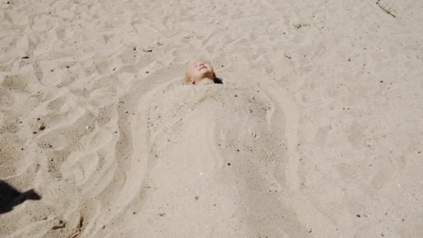 Niña solitaria acostada en la playa del mar en la arena. Imágenes amplias. — Vídeo de stock