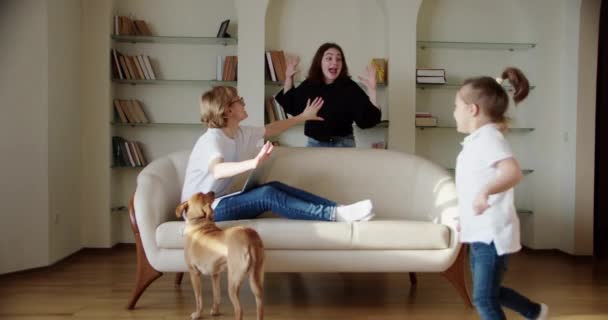 Müde Frau sitzt auf der Couch, genervt, während eine laute kleine Tochter schreit, springt auf die Couch. Zeitlupenaufnahmen — Stockvideo